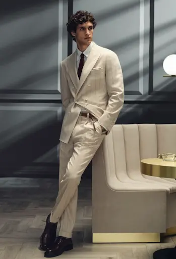 Man wearing a cream pinstripe double-breasted custom suit with a white shirt, burgundy tie, and dark derby shoes