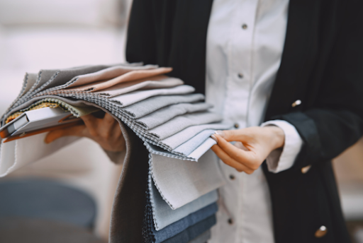 Tailor fanning out suit fabric swatches in greys, blues and beige to match lining against cloth