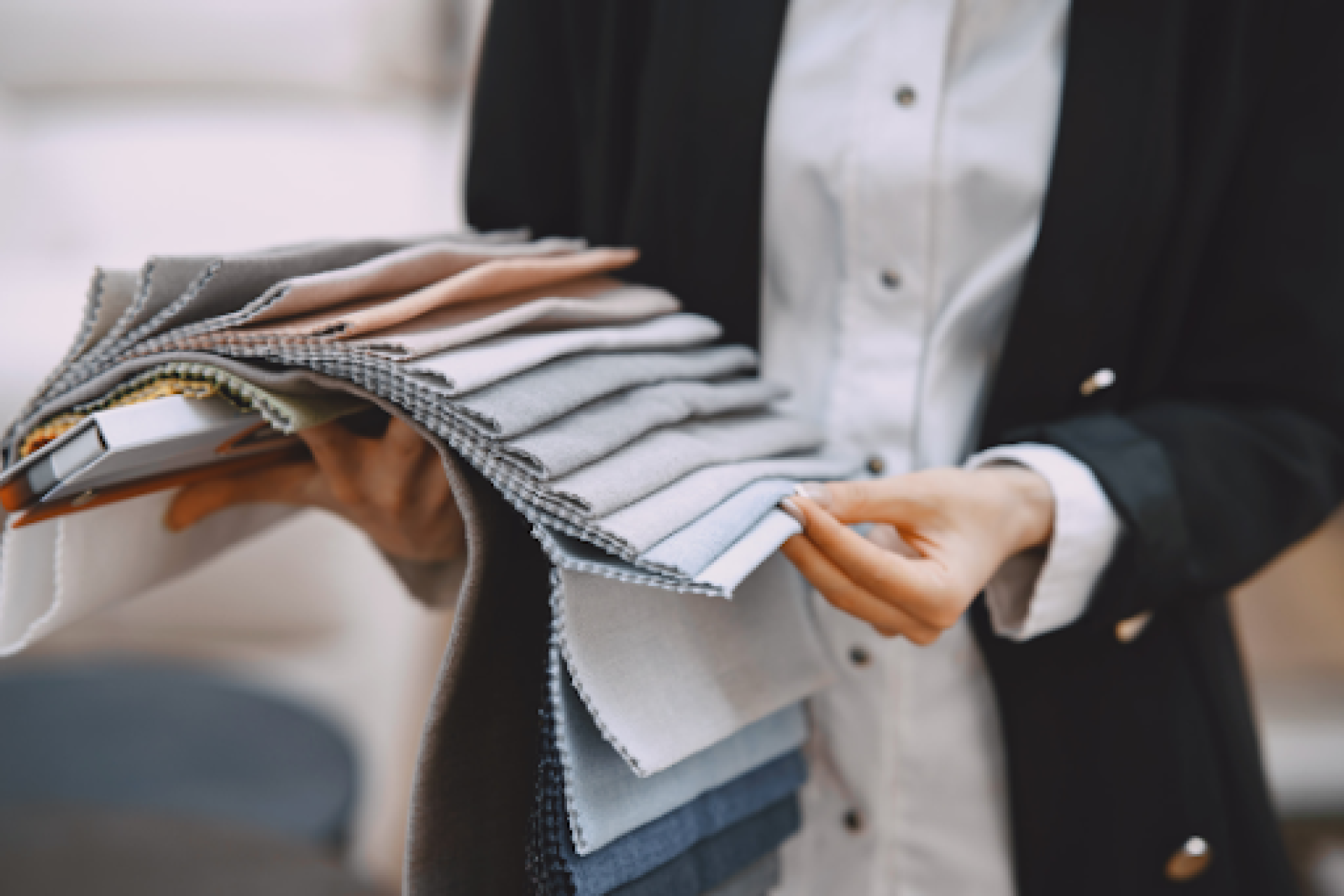 Tailor fanning out suit fabric swatches in greys, blues and beige to match lining against cloth