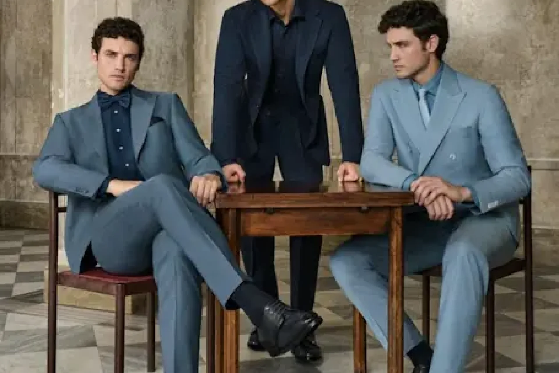 Three men pairing blue suits with navy shirts, a bow tie and a knitted tie in tonal colour combinations